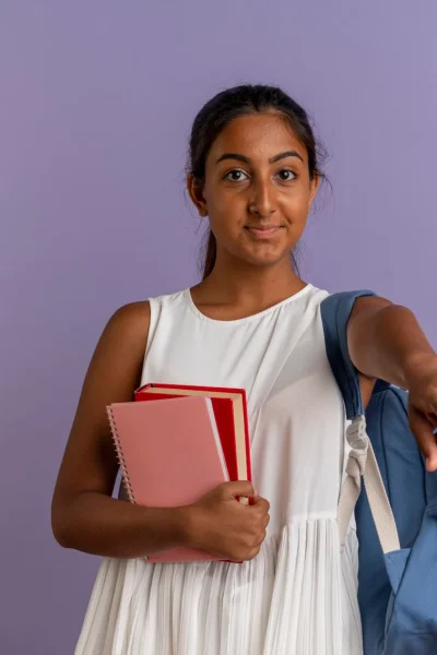 pleased-young-schoolgirl-wearing-back-bag-holding-book-with-notebook-showing-you-gesture-purple1-2048x1454.jpg
